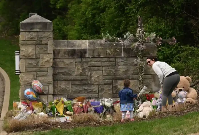 A woman and child bring flowers on March 28, 2023, to the entry to The Covenant School in Nashville, Tenn., where six people were killed in a mass shooting the day before.